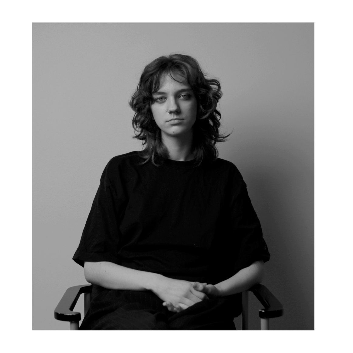 Black and white studio portrait of a student sitting on a chair