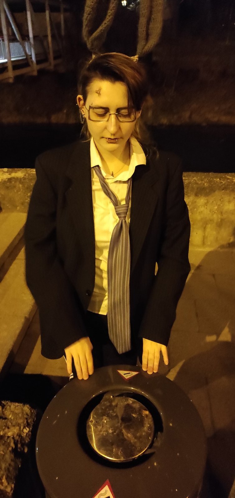 Bunny character in glasses standing over a trash bin at night